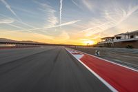 a photo of a dirt race track with sun setting in the distance of the track