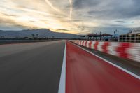 a photo of a dirt race track with sun setting in the distance of the track