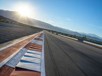 a photo of a dirt race track with sun setting in the distance of the track