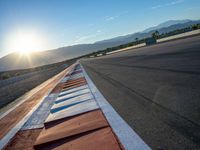 a photo of a dirt race track with sun setting in the distance of the track