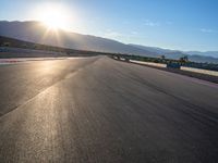 a photo of a dirt race track with sun setting in the distance of the track