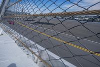 an airport fence with a car driving on it next to the tarmac and runway