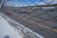 an airport fence with a car driving on it next to the tarmac and runway