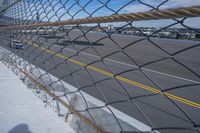 an airport fence with a car driving on it next to the tarmac and runway