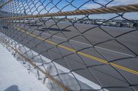 an airport fence with a car driving on it next to the tarmac and runway