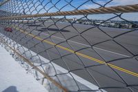 an airport fence with a car driving on it next to the tarmac and runway