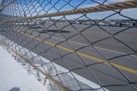 an airport fence with a car driving on it next to the tarmac and runway