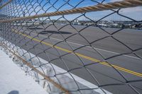 an airport fence with a car driving on it next to the tarmac and runway