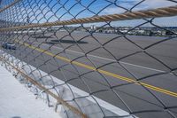 an airport fence with a car driving on it next to the tarmac and runway