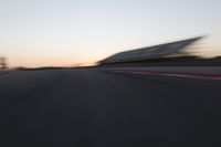 blurred speed - moving image of a race track at sunset with red and white stripes