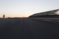 blurred speed - moving image of a race track at sunset with red and white stripes