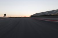 blurred speed - moving image of a race track at sunset with red and white stripes