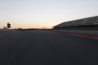 blurred speed - moving image of a race track at sunset with red and white stripes