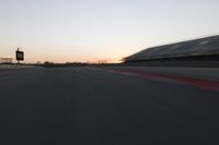 blurred speed - moving image of a race track at sunset with red and white stripes