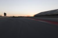 blurred speed - moving image of a race track at sunset with red and white stripes