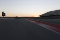 blurred speed - moving image of a race track at sunset with red and white stripes