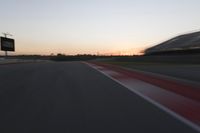 blurred speed - moving image of a race track at sunset with red and white stripes