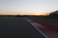 blurred speed - moving image of a race track at sunset with red and white stripes