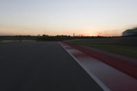 blurred speed - moving image of a race track at sunset with red and white stripes