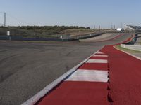 an empty track at a motorsports club with some red and white stripeing on it