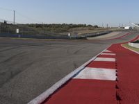 an empty track at a motorsports club with some red and white stripeing on it