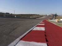 an empty track at a motorsports club with some red and white stripeing on it