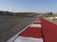 an empty track at a motorsports club with some red and white stripeing on it