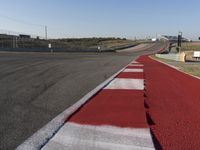 an empty track at a motorsports club with some red and white stripeing on it