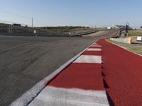 an empty track at a motorsports club with some red and white stripeing on it