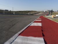 an empty track at a motorsports club with some red and white stripeing on it