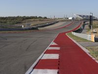 an empty track at a motorsports club with some red and white stripeing on it