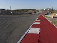 an empty track at a motorsports club with some red and white stripeing on it