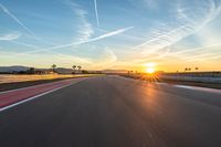 a photo of a dirt race track with sun setting in the distance of the track