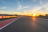 a photo of a dirt race track with sun setting in the distance of the track