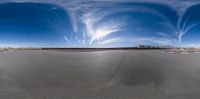 the photo of an empty parking lot is seen from inside a fisheye lens and shows the view from a angle on a sunny day