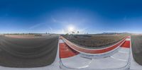 two spherical images of a dirt field and a red road in front of the sun