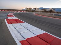 a photo of a dirt race track with sun setting in the distance of the track