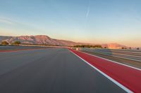 a photo of a dirt race track with sun setting in the distance of the track