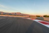 a photo of a dirt race track with sun setting in the distance of the track