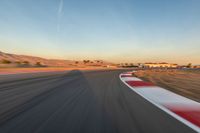 a photo of a dirt race track with sun setting in the distance of the track