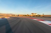 a photo of a dirt race track with sun setting in the distance of the track