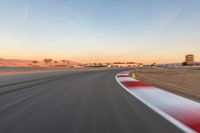 a photo of a dirt race track with sun setting in the distance of the track