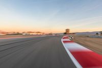 a photo of a dirt race track with sun setting in the distance of the track