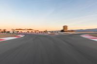 a photo of a dirt race track with sun setting in the distance of the track