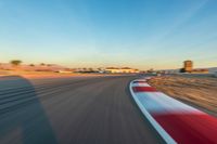 a photo of a dirt race track with sun setting in the distance of the track