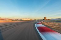 a photo of a dirt race track with sun setting in the distance of the track