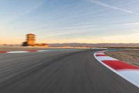 a photo of a dirt race track with sun setting in the distance of the track