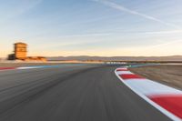 a photo of a dirt race track with sun setting in the distance of the track