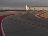 a track that has a red line going around it near a building with a view on a cloudy sky