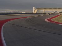 a track that has a red line going around it near a building with a view on a cloudy sky